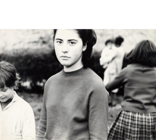 Mario Giacomelli, “A Silvia”, 1964. Figura femminile in primo piano con sullo sfondo una madre con in braccio un bambinoCourtesy CRAF – Centro di Ricerca ed Archiviazione della Fotografia, Spilimbergo.